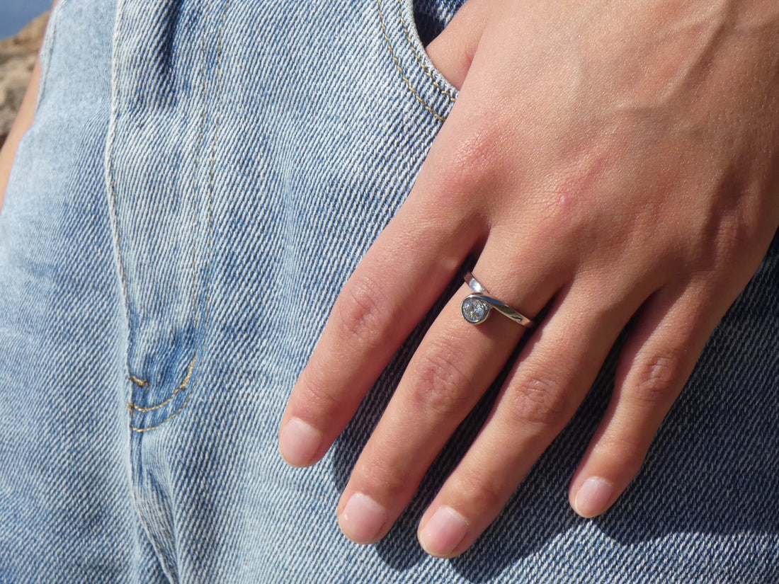 Frau trägt einen silbernen Edelstahlring mit einem Zirkonia Stein und steckt die Hand halb in ihre Jeanshose